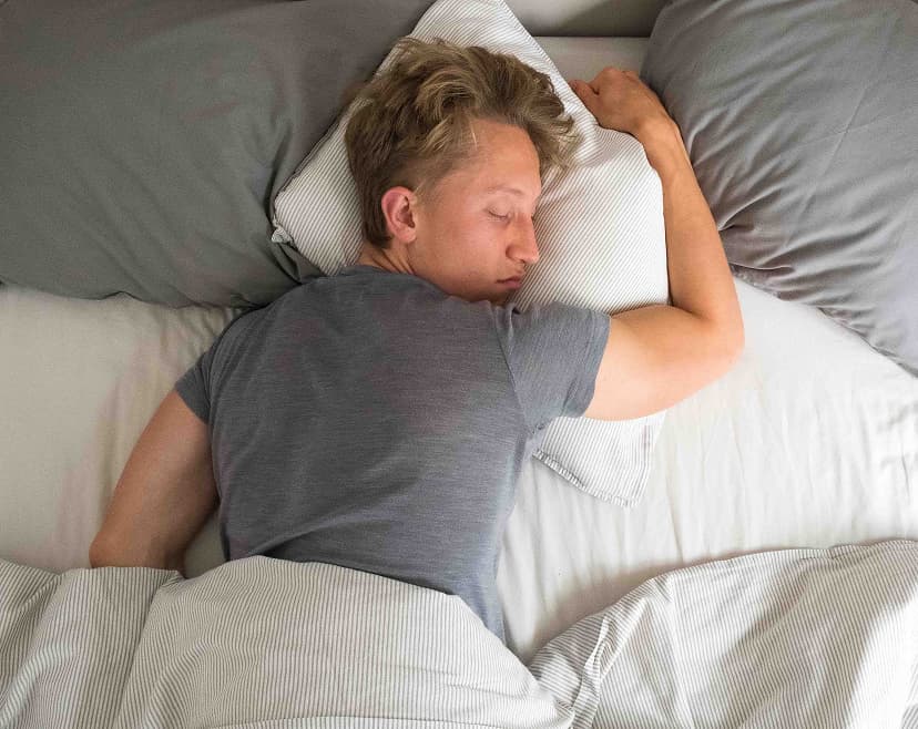 Erschöpfter Mann liegt schlafend im Bett